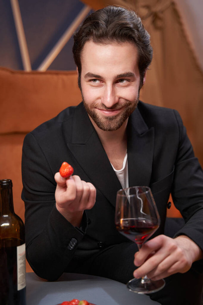 Male with wine offering strawberry to another person - Foto, Bild