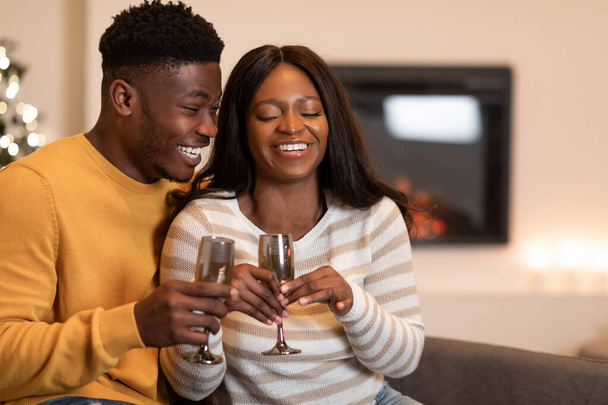 喜びに満ちたアフリカ系アメリカ人の配偶者がバレンタインを祝うガラスを保持屋内で笑う - 写真・画像