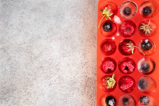 Frozen berries in ice cubes covered with hoarfrost. Homemade food. Top view. - Foto, afbeelding