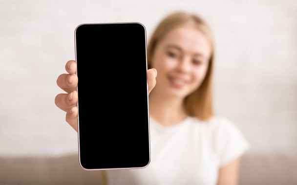 Jeune femme montrant smartphone avec grand écran blanc à la caméra, dame démontrant l'espace pour application mobile ou site Web - Photo, image