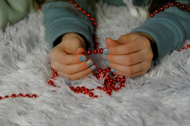 Close-up of the hand of a little girl who is sorting red beads in her hands. Baby and beads - Fotoğraf, Görsel