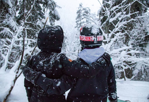 Two girls with a snowboards in the forest in the mountains and the snowfall - Photo, Image