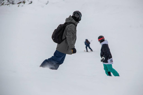 Snowboardcular dağın yamacından aşağı iniyor. - Fotoğraf, Görsel