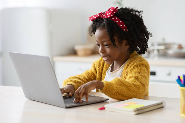 Дистанційне навчання. Мила маленька чорна дівчинка Дослідження з ноутбуком вдома
 - Фото, зображення