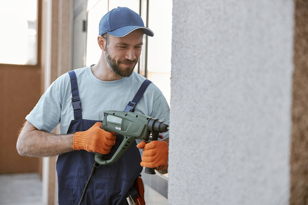 Bearded young man drilling wall with hammer drill - Foto, immagini
