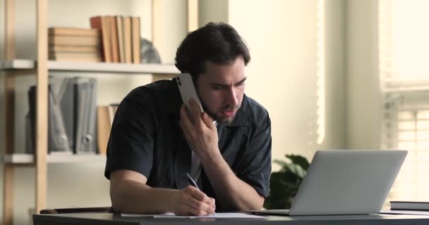 Employee noting received information while talk to client on cellphone - Imágenes, Vídeo