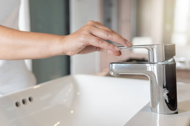 Close up Woman open chrome faucet washbasin to washing hands rubbing with soap for corona virus at water tap. Faucet and water drop off. Bathroom interior with sink basin and water tap. Tap water down. - Foto, imagen