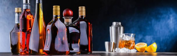 Bottiglie di bevande alcoliche assortite e un barista che prepara un drink con uno shaker da cocktail - Foto, immagini