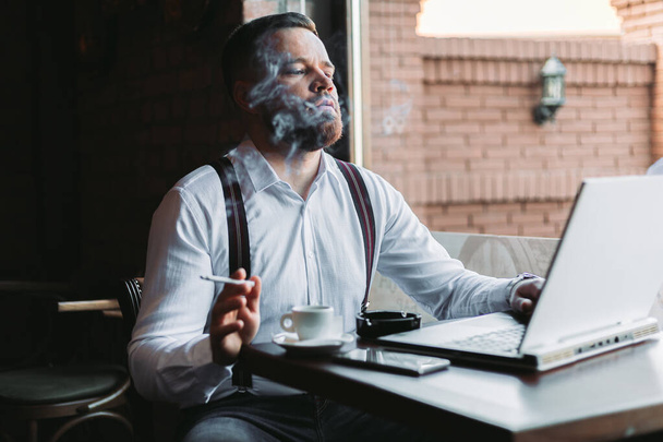 Young businessman working in a cafe, smoking - 写真・画像