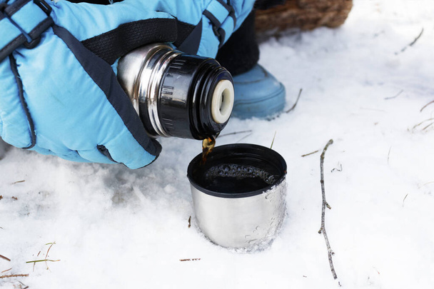 pouring warm tea in a mug from thermos . Winter tourism, sports and travel concept. - Fotó, kép