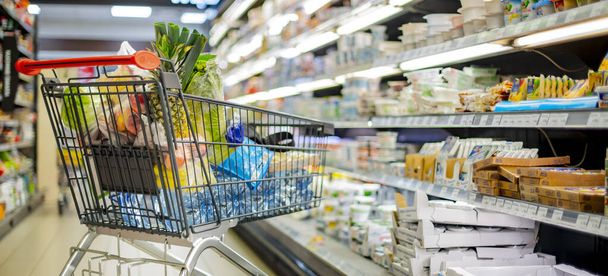 Un panier avec des produits d'épicerie dans un supermarché - Photo, image
