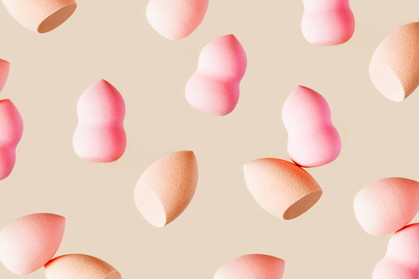 Pattern with cosmetic sponge pink beige colored. Soft makeup sponge beauty blender, brush for face skin, facial applicator. Backgrounds for salon fashion beauty makeup - Photo, Image
