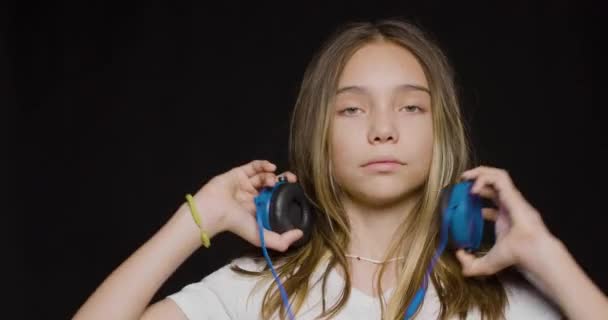 Teenage girl wearing headphones and listening to the hard rock music over black background. - Séquence, vidéo