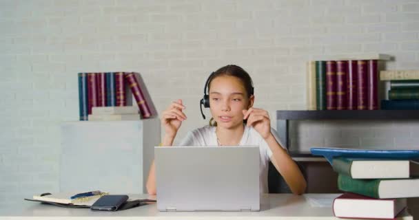 Teenage girl during an online conversation in front of a laptop monitor. She talks, smiles and gestures. - Video