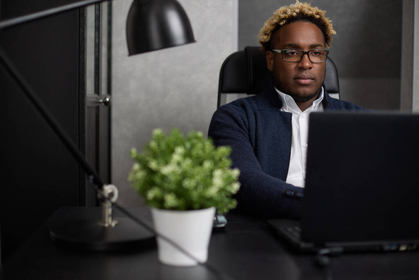 Confident mature businessman working on a black laptop in a modern office. - Zdjęcie, obraz