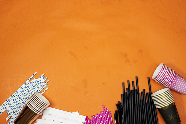 concepto feliz cumpleaños, pajitas y vasos desechables con papel toalla aislado sobre fondo naranja - Foto, Imagen