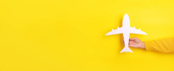 mano sosteniendo avión sobre fondo amarillo, diseño panorámico - Foto, imagen