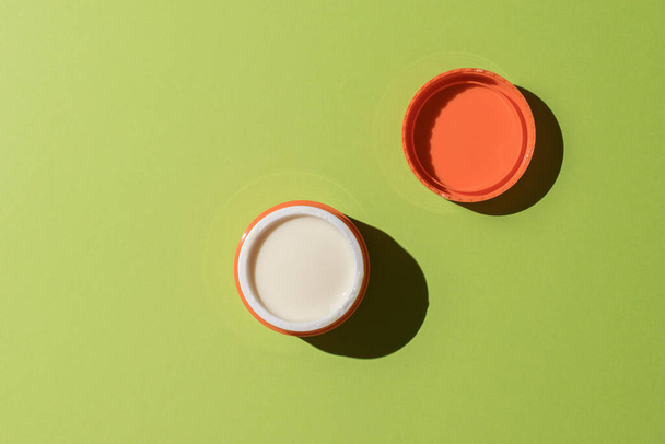 An open jar with cosmetic cream on a green background. A skin care product. - Fotó, kép