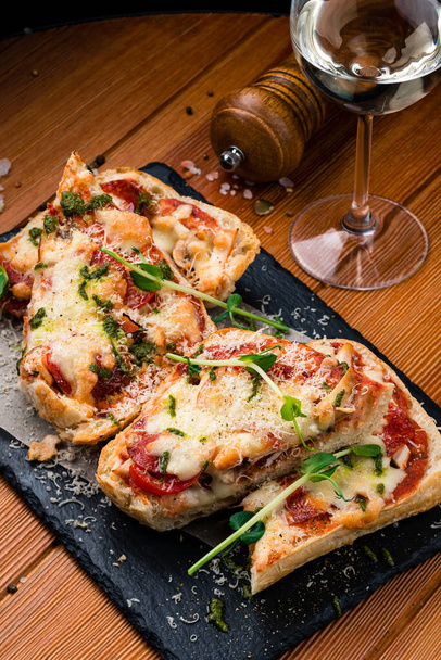 homemade pizza slices, Homemade sliced classic italian pizza copy space top view. Flatbread pizza garnished with fresh arugula on wooden pizza board - Photo, image