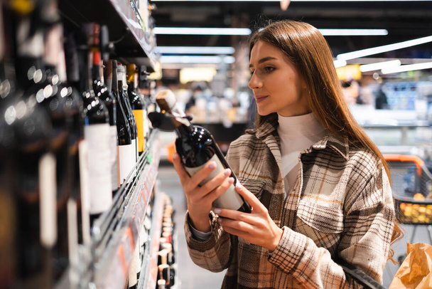 Γυναίκα επιλέγοντας το κρασί στο σούπερ μάρκετ - Φωτογραφία, εικόνα
