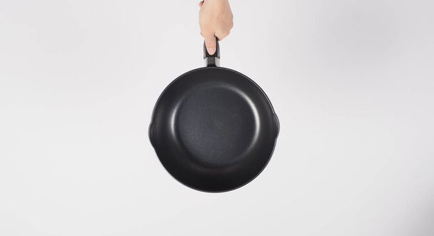 Cleaning Electric non stick pan. Hand on white background cleaning the non stick pan with handy dish washing sponge which yellow color on the soft side and green on hard side for hygiene after cook. - Fotó, kép