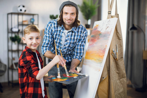Happy father and son drawing together on easel - Fotografie, Obrázek