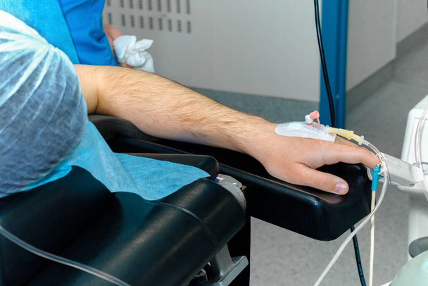 Intravenous drip catheter in the patients hand on the operating table. - Foto, Bild