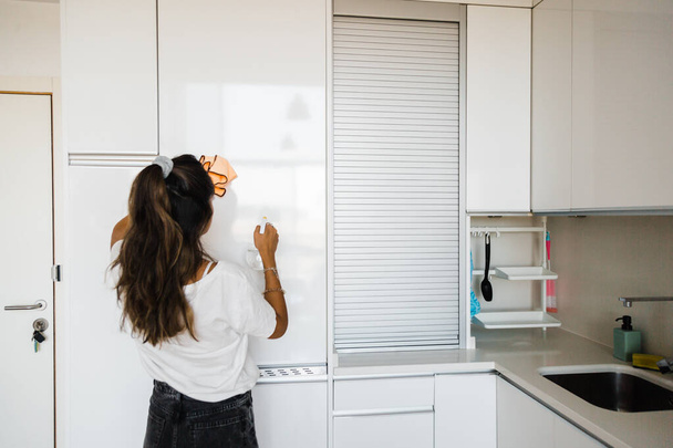 молода жінка прибирає білу і яскраву кухню
 - Фото, зображення