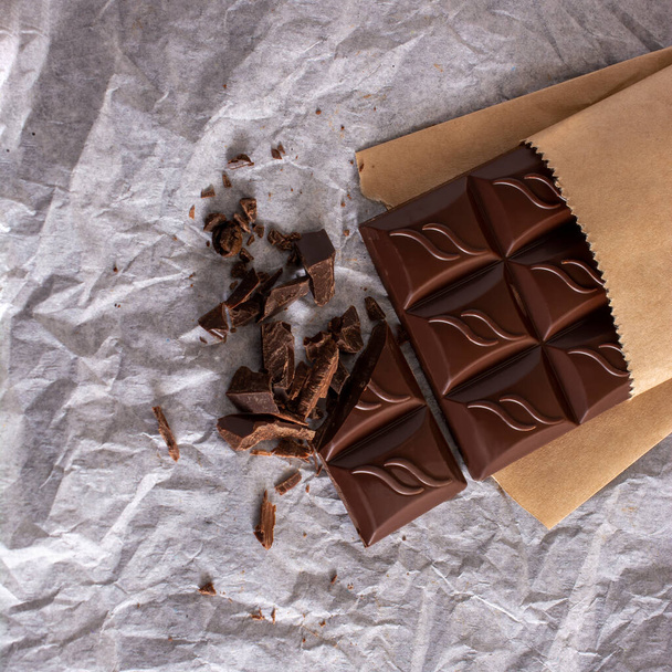 open chocolate bar on white packaging crumpled paper. copy space. flatlay. - 写真・画像