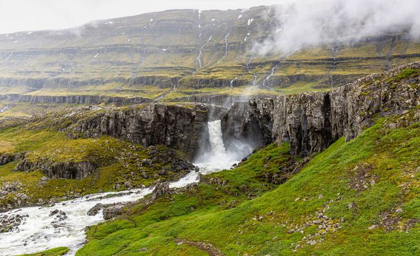 Van dichtbij een wilde waterval in IJsland. - Foto, afbeelding