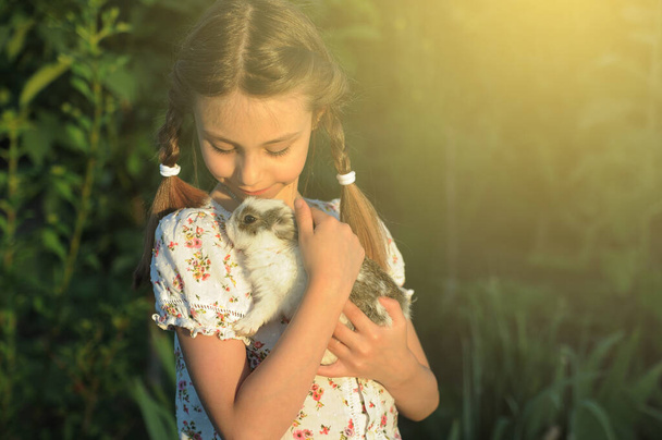 Das Kind umarmt einen kleinen Hasen. Ostersymbol. Freundschaft zwischen Kind und Tier. - Foto, Bild