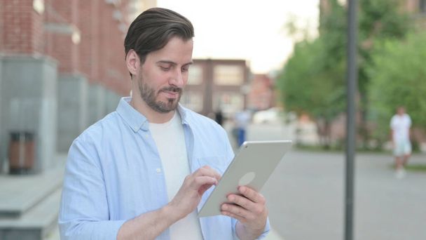 Man Browing Internet on Tablet while Standing Outdoor - Photo, Image