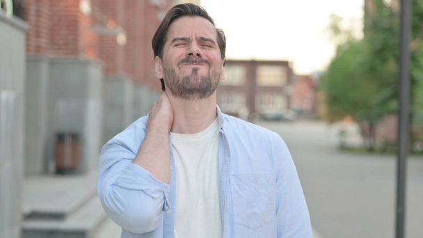 Człowiek mając ból szyi podczas stania na zewnątrz - Zdjęcie, obraz