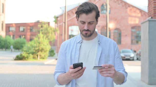 Ο άνθρωπος που έχει σε απευθείας σύνδεση επιτυχία πληρωμής στο Smart Phone στο δρόμο - Φωτογραφία, εικόνα