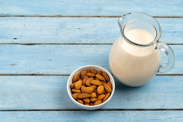 almond milk in a glass carafe on a blue wooden background, space for text - Foto, afbeelding