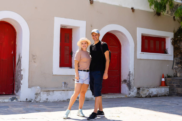 couple in front of a red wooden door in Greece - Foto, afbeelding