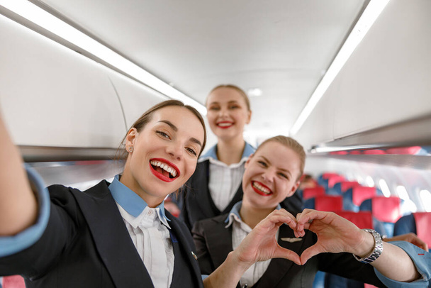 Cheerful flight attendants having fun in airplane - Foto, Bild
