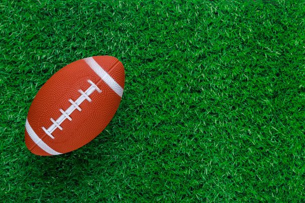 Green grass sports field with american football ball. Football game background. - Foto, Imagen
