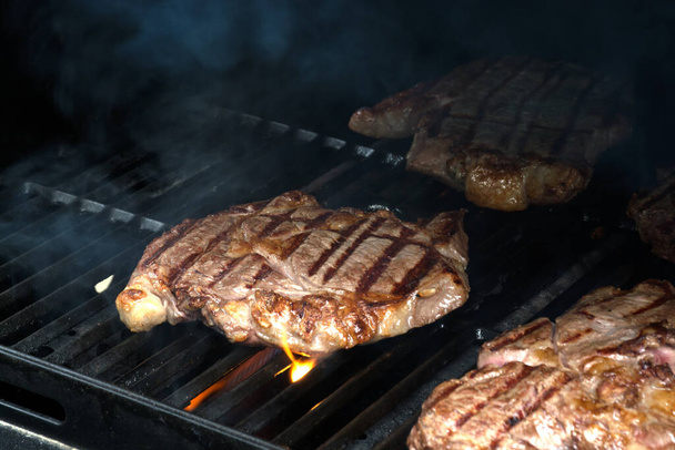 Fresh grilled meat, beef or pork. Grilling steaks on flaming grill - Zdjęcie, obraz
