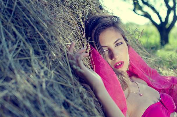 Brunette woman lying on hay - 写真・画像