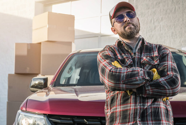 Proud Caucasian Contractor Worker in His 30s Wearing Sunglasses Next to His Modern Pickup Truck and Cargo Boxes. Supplies Delivery Theme. - Фото, изображение