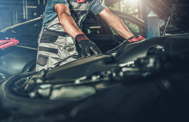 Automotive Industry Concept. Car Mechanic Looking Under Vehicle Hood and Preparing For Scheduled Maintenance Inside Dealer Service Area.  - Foto, afbeelding