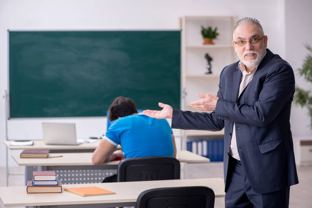 Old male teacher and young male student in front of blackboard - Photo, Image