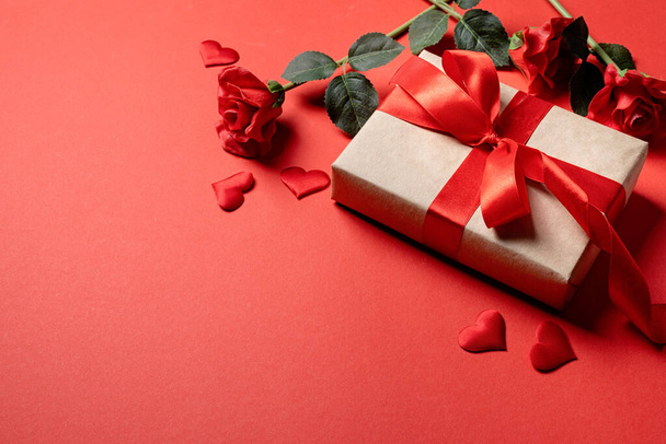Fondo sólido rojo con corazones rojos, regalos y confeti. El concepto de San Valentín. - Foto, Imagen