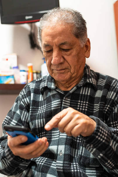 Happy senior Caucasian man looking at cellphone screen browse wireless internet. Smiling modern mature 70s grandfather text or message on smartphone. Elderly use cell technologies at home. - Photo, Image
