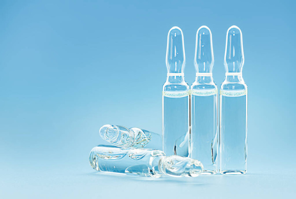 five transparent ampoules with medicine on a blue background - Фото, изображение