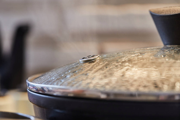 Frying pan lid with drops and steam close-up, in the kitchen - Zdjęcie, obraz