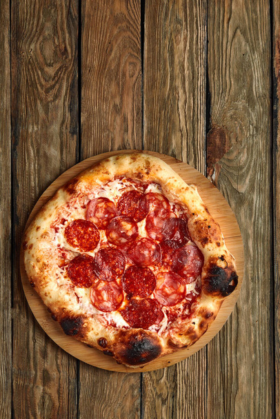 Pfefferoni-Pizza auf rustikalem Holz im Vintage-Stil. Ansicht von oben - Foto, Bild