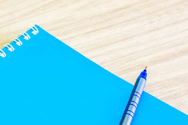 Bolígrafo azul y azul en blanco libro de portada vacía espiral papelería útiles escolares para la educación idea de negocios libro de portada de diseño nota pad memo sobre fondo de madera. - Foto, Imagen