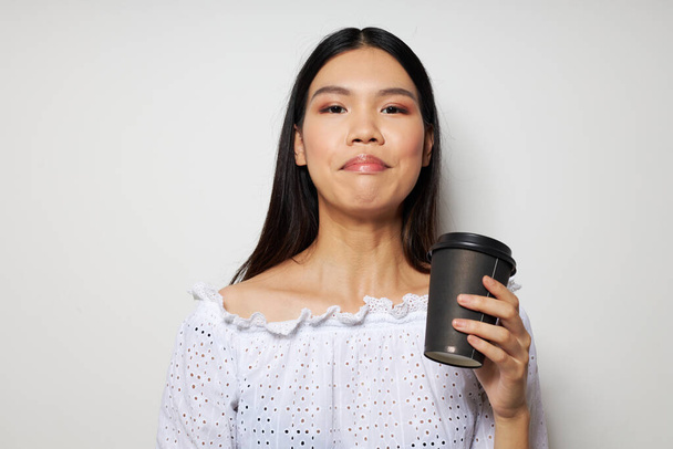 Charming young Asian woman posing with a disposable glass of fun drink studio model unaltered - Photo, image